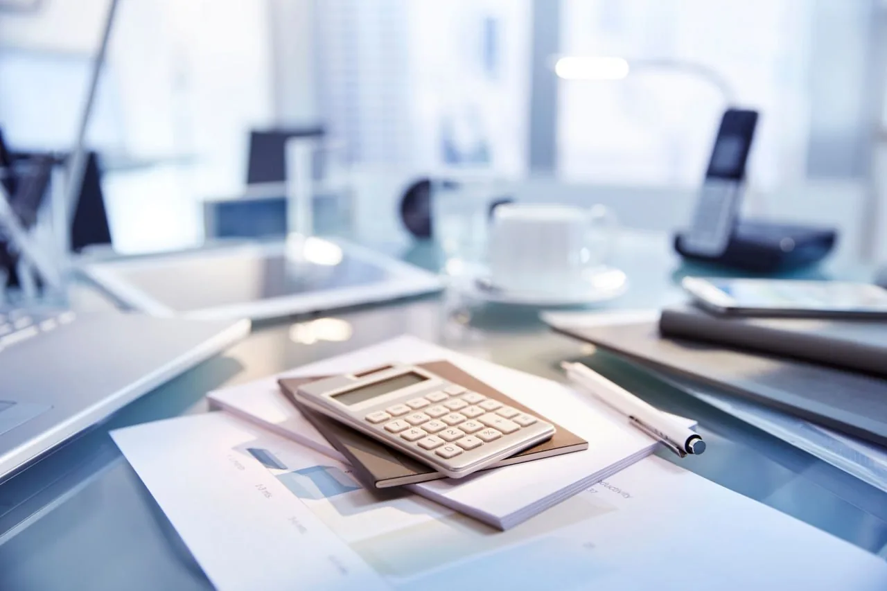 Рабочий стол с калькулятором и бумагами для анализа показателей продаж в Excel